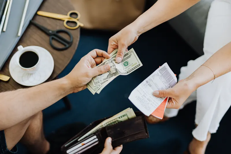 An overhead view of a customer paying cash and receiving an itemized receipt